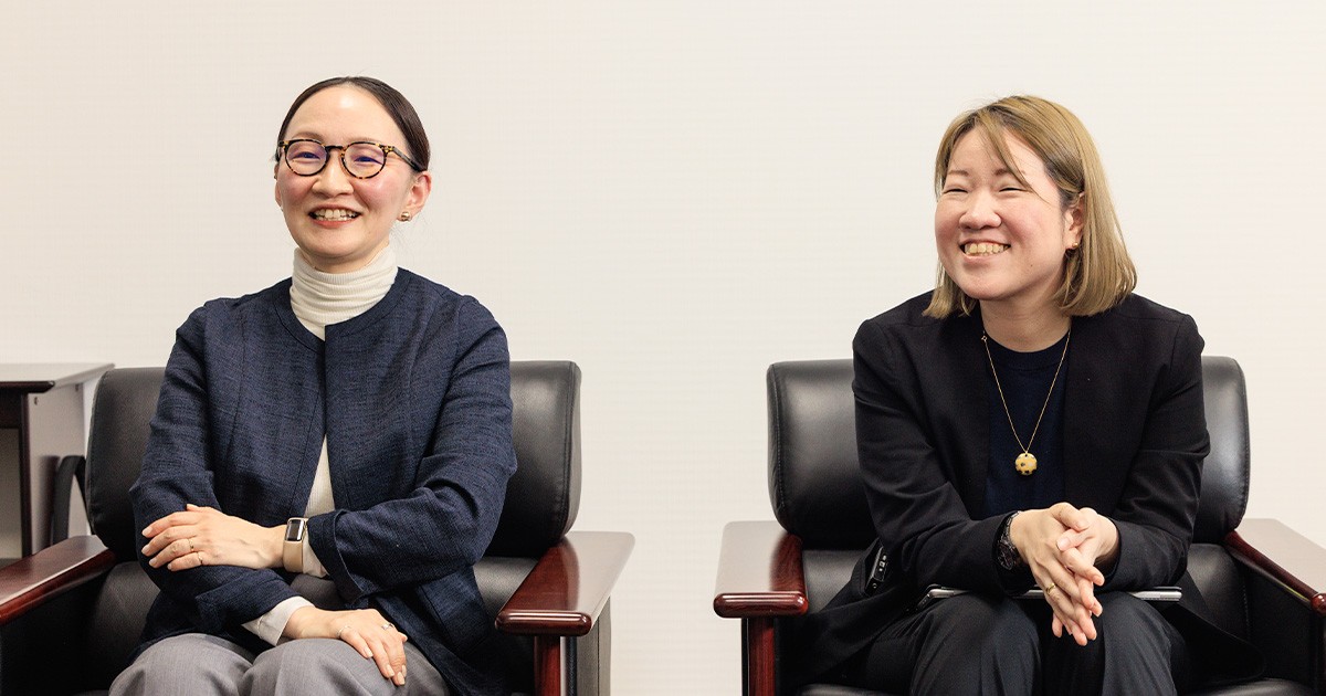 写真：左から新山、三木 美呂句/ デジタル戦略部（ビジネス・アーキテクツ）が笑顔で話している様子。