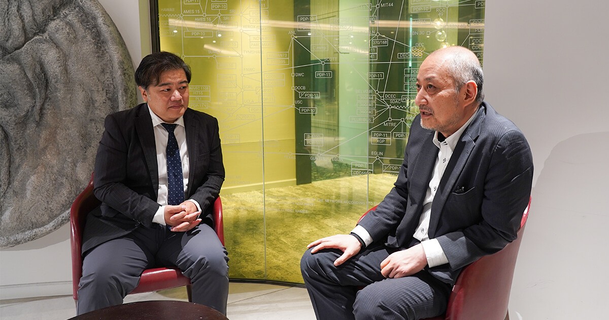 写真;株式会社ジーニー平井氏が話し、株式会社ビジネス・アーキテクツ浦が聞く様子